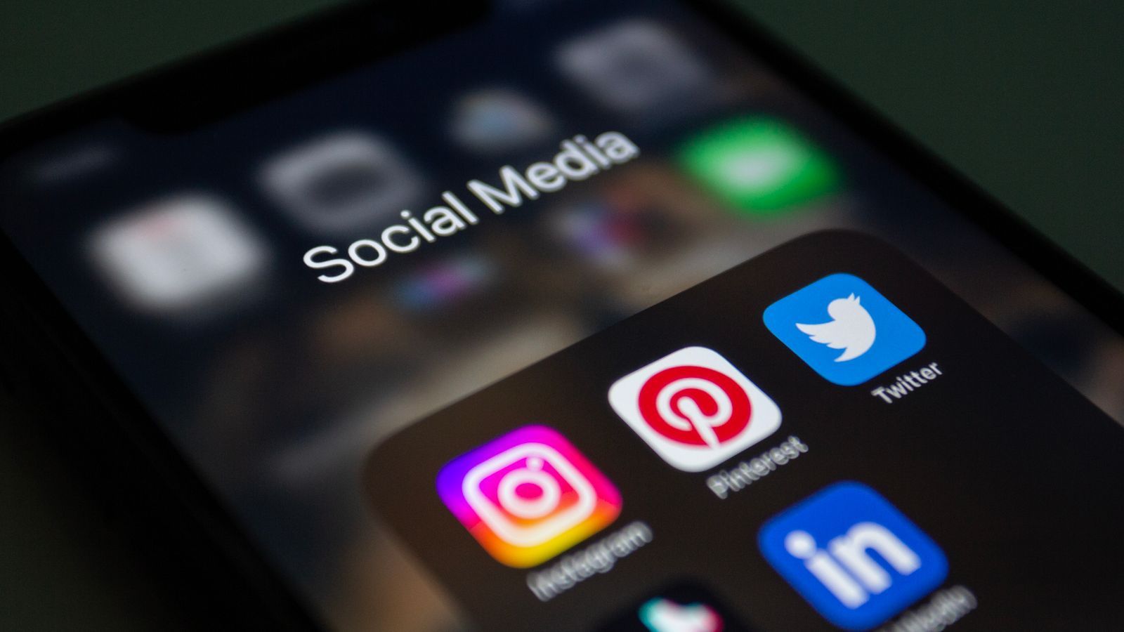 A close-up of a phone screen showing a home screen folder titled Social Media with Instagram, Pinterest, Twitter and LinkedIn icons