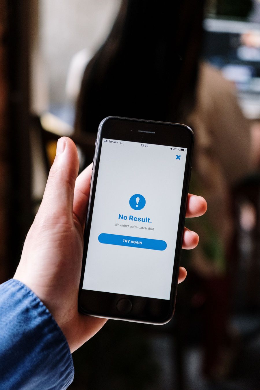 A hand holding an iPhone that shows a "No Result" message with a Try Again button