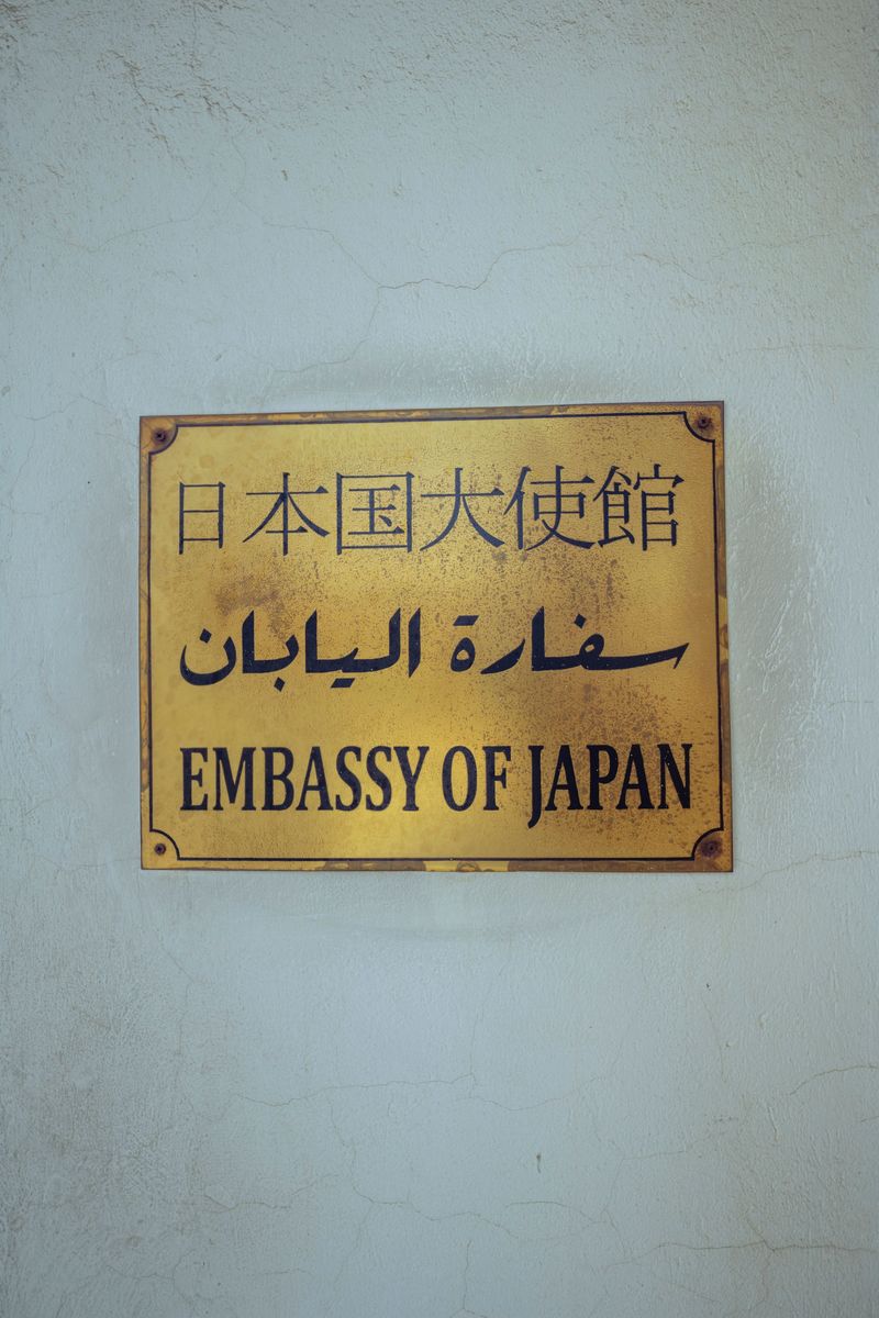 A gold plaque reading Embassy of Japan in Japanese, Arabic and English on a pale wall