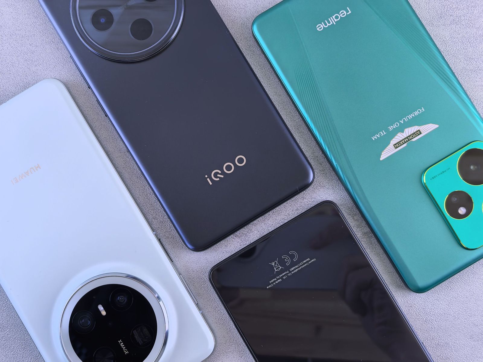 Several Android smartphones of different sizes and colors laid flat on a light surface