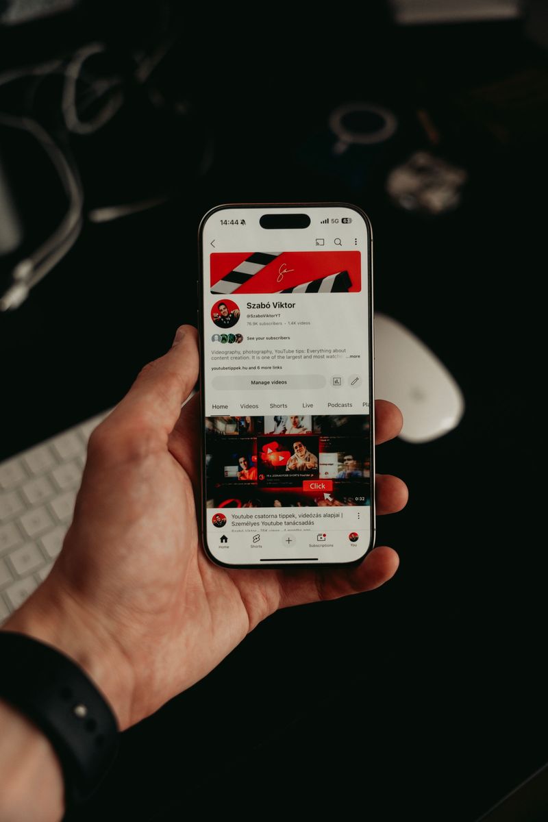 A hand holding a smartphone with a dark, image-led app open on the screen