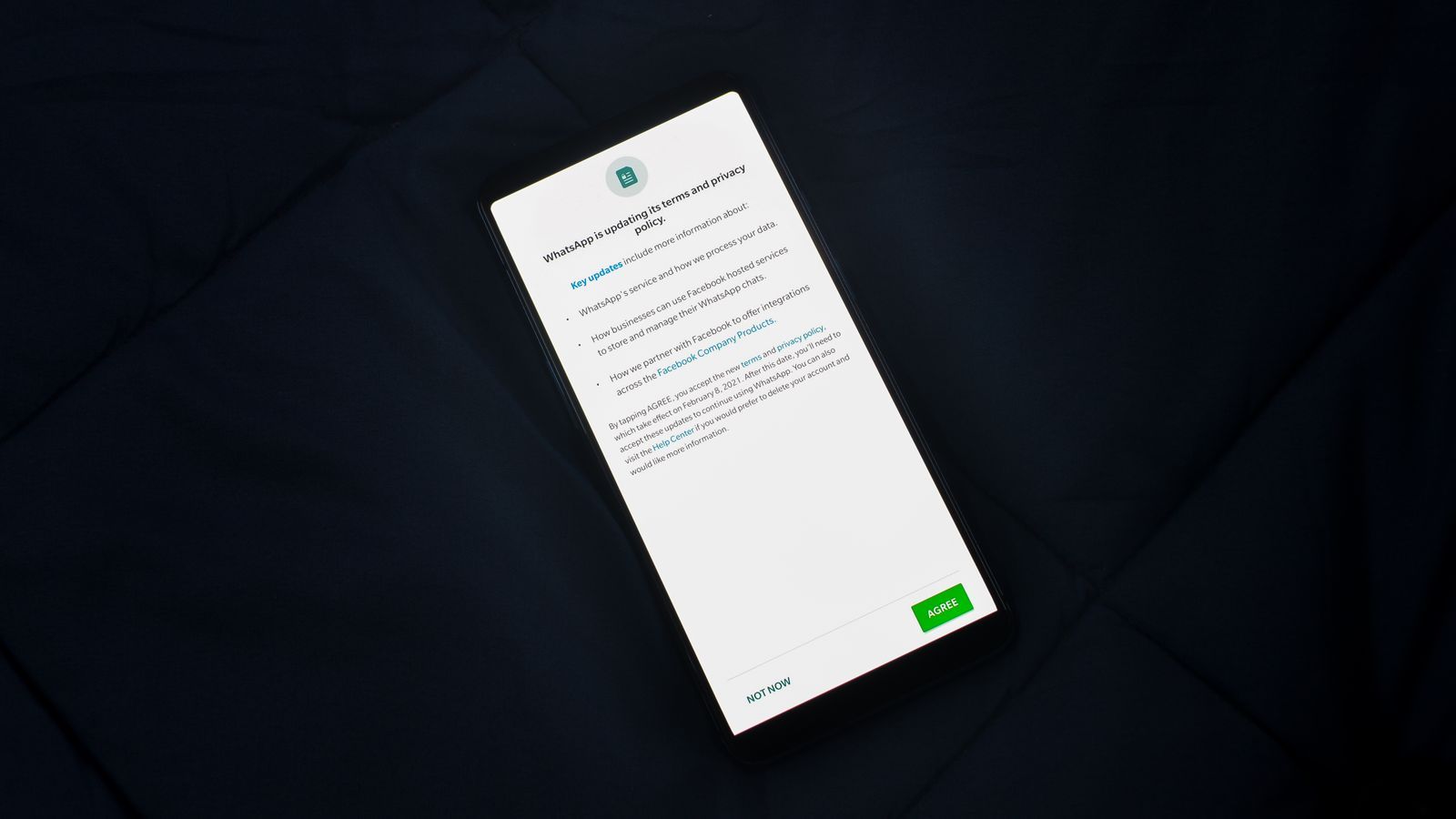 A smartphone lying on dark fabric, showing a full-screen privacy policy update with an Agree button and a Not now link