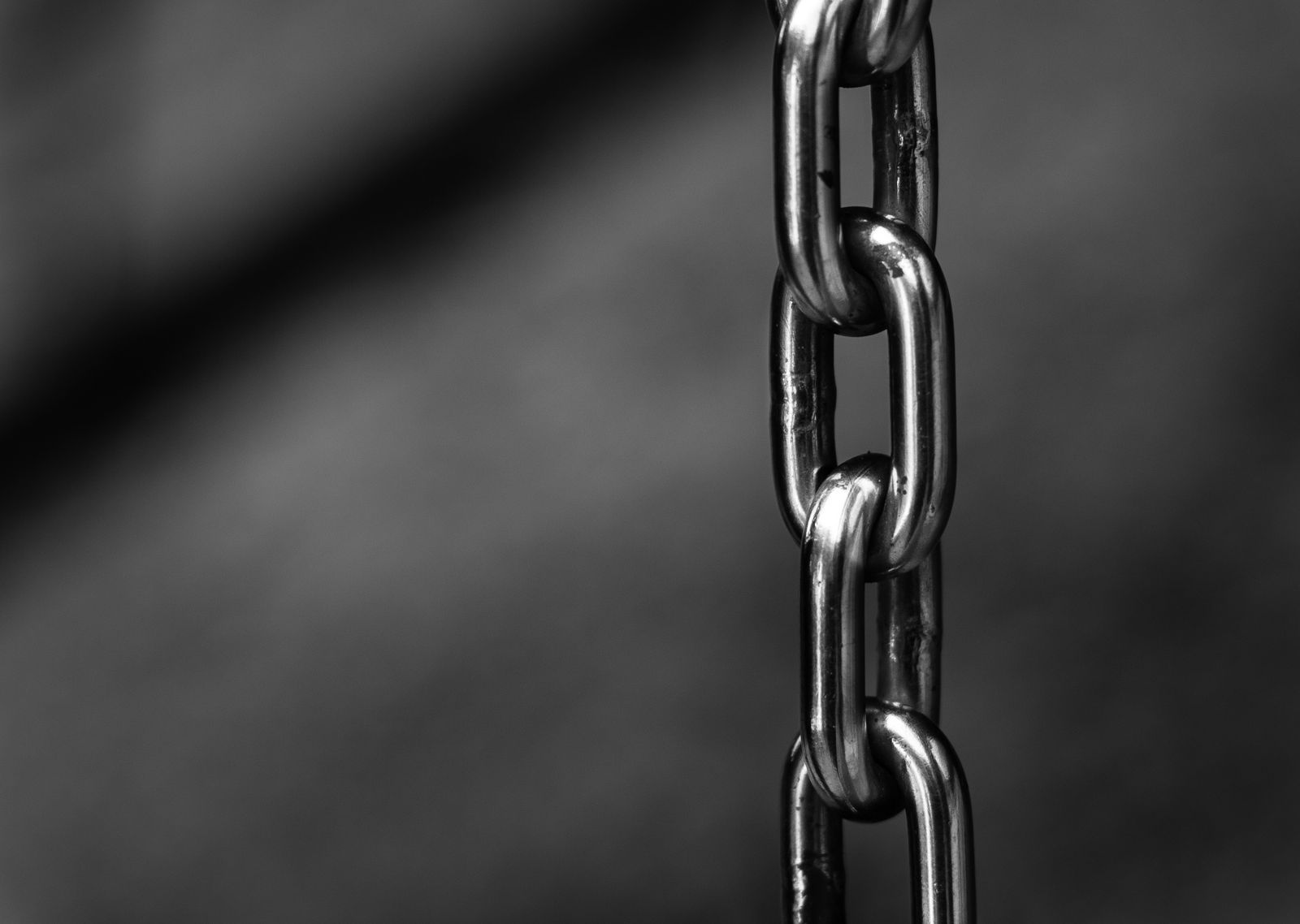 A short length of polished steel chain hanging against a dark grey background
