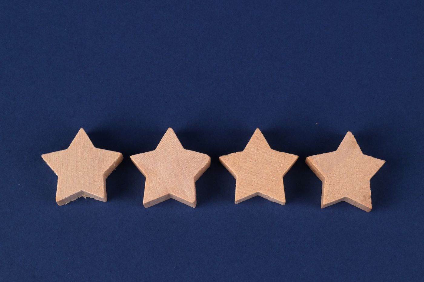 Four wooden stars in a row on a deep blue background