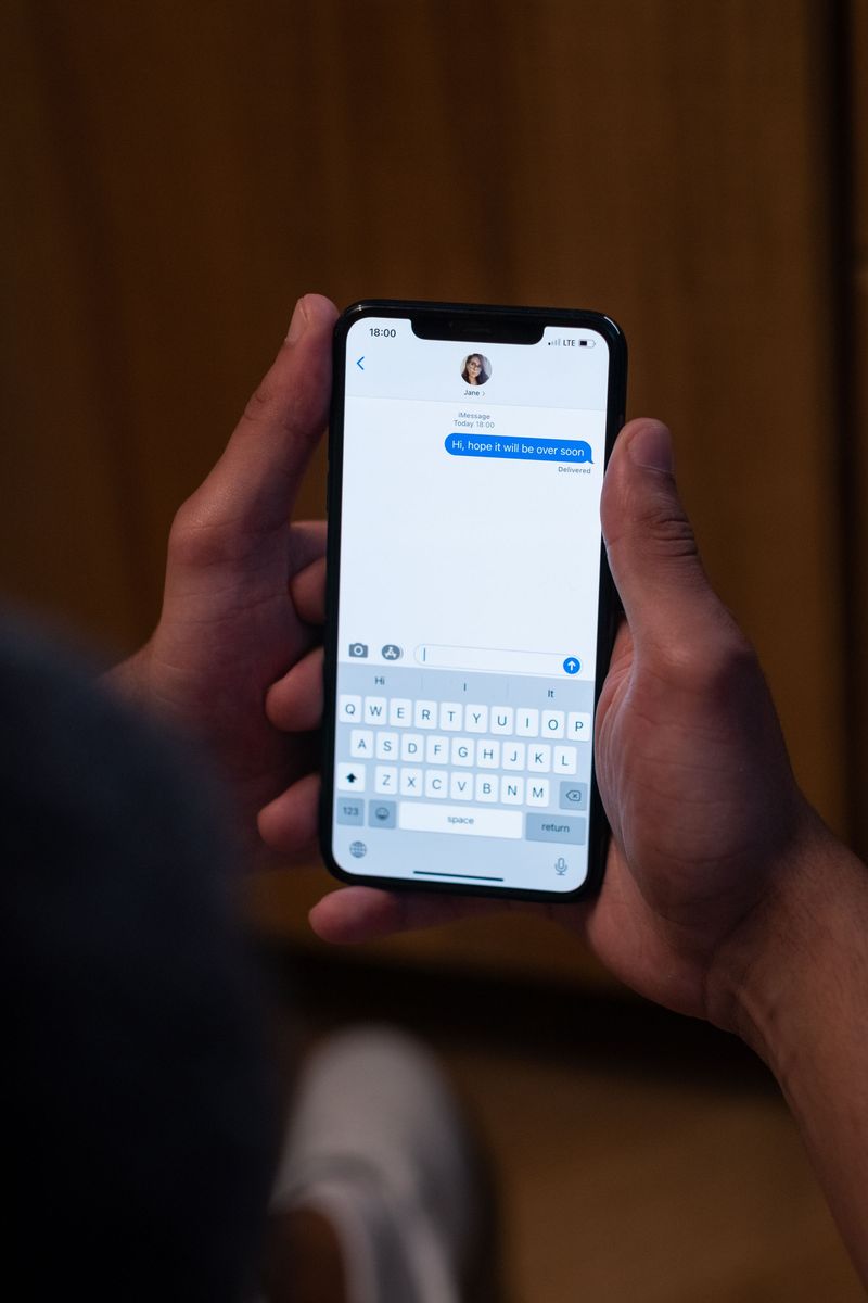 Two hands holding a smartphone and typing a short message on the on-screen keyboard