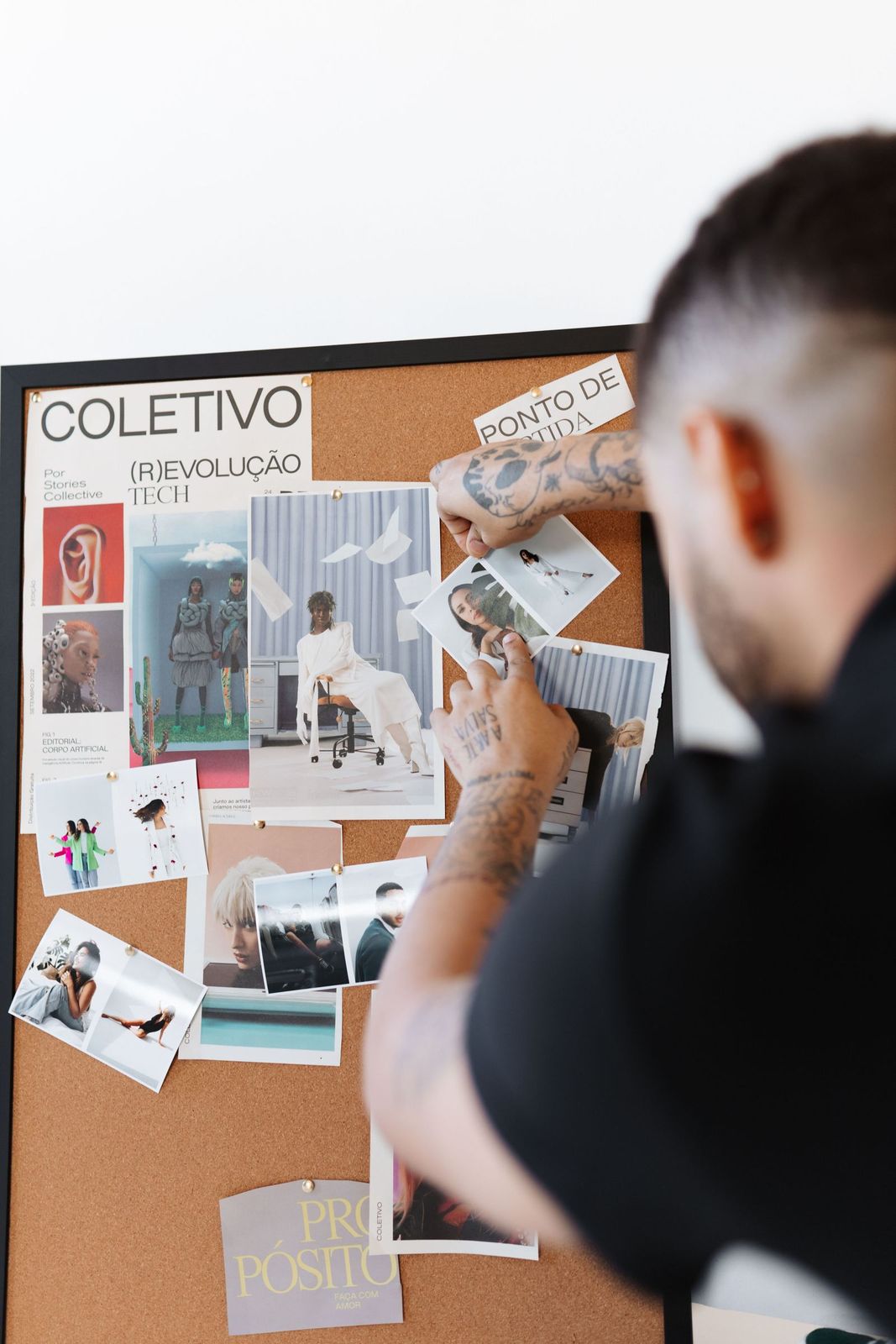 A man pinning photos and notes to a cork bulletin board
